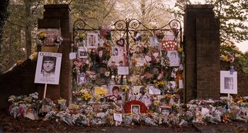 Movie still from “Submarine” (2010), directed by Richard Ayoade – A fence covered in flowers and pictures of people; Wide shot, High angle