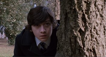 Movie still from “Submarine” (2010), directed by Richard Ayoade – A young man leaning against the side of a tree; Close Up shot, High angle