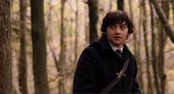 Movie still from “Submarine” (2010), directed by Richard Ayoade – A young man in a black coat and a tie; Medium shot, Over the shoulder angle