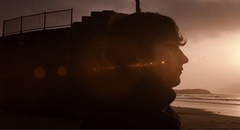 Movie still from “Submarine” (2010), directed by Richard Ayoade – A man is standing on the beach at sunset; Close Up shot, Low angle