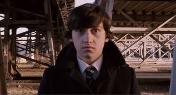 Movie still from “Submarine” (2010), directed by Richard Ayoade – A young man in a black coat and a tie; Close Up shot, High angle