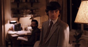 Movie still from “Submarine” (2010), directed by Richard Ayoade – A man in a suit and tie standing in front of another man in a suit and tie; Medium shot, Over the shoulder angle