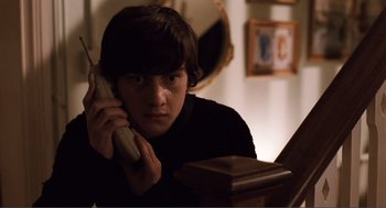 Movie still from “Submarine” (2010), directed by Richard Ayoade – A man sitting at a table talking on a phone; Medium shot, High angle