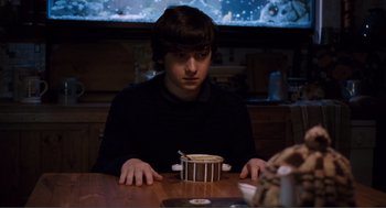 Movie still from “Submarine” (2010), directed by Richard Ayoade – A man sitting at a table with a bowl of food; Medium shot, High angle