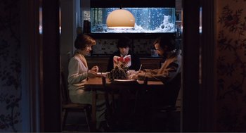 Movie still from “Submarine” (2010), directed by Richard Ayoade – Three people sitting at a table in front of a television; Wide shot, High angle