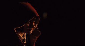 Movie still from “Submarine” (2010), directed by Richard Ayoade – A person wearing a hooded jacket in the dark; Close Up shot, High angle