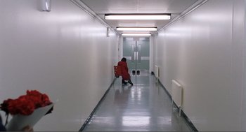 Movie still from “Submarine” (2010), directed by Richard Ayoade – A person kneeling down in the hallway of a building; Extreme Wide shot, High angle