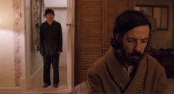 Movie still from “Submarine” (2010), directed by Richard Ayoade – A man standing in front of another man in a room; Medium shot, Over the shoulder angle