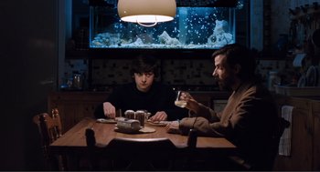 Movie still from “Submarine” (2010), directed by Richard Ayoade – Two men sitting at a table in front of a fish tank; Medium shot, Over the shoulder angle