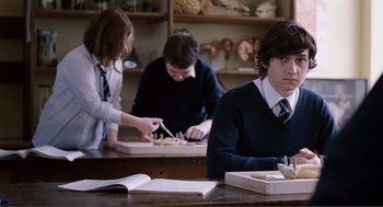 Movie still from “Submarine” (2010), directed by Richard Ayoade – Three students are sitting at a table in a classroom; Medium shot, Over the shoulder angle
