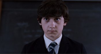 Movie still from “Submarine” (2010), directed by Richard Ayoade – A young man in a suit and a tie in front of a chalkboard; Close Up shot, High angle