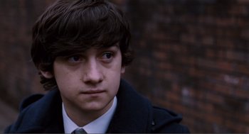Movie still from “Submarine” (2010), directed by Richard Ayoade – A young man wearing a suit and tie looking at the camera; Close Up shot, High angle