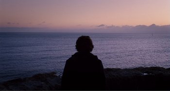 Movie still from “Submarine” (2010), directed by Richard Ayoade – A person standing on the beach looking out at the ocean; Wide shot, Low angle