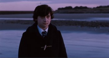 Movie still from “Submarine” (2010), directed by Richard Ayoade – A young man wearing a coat and a tie; Medium shot, High angle