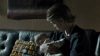 Movie still from “Submarino” (2010), directed by Thomas Vinterberg – A woman holding a baby in her arms on a couch; Close Up shot, Low angle