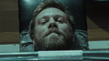 Movie still from “Submarino” (2010), directed by Thomas Vinterberg – A man with a beard is laying down; Close Up shot, Overhead angle