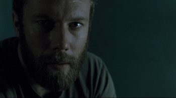 Movie still from “Submarino” (2010), directed by Thomas Vinterberg – A person with a beard looking at the camera; Close Up shot, Low angle