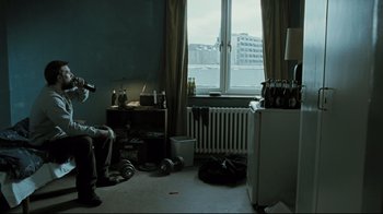 Movie still from “Submarino” (2010), directed by Thomas Vinterberg – A man sitting in front of a window in a living room; Wide shot, Low angle