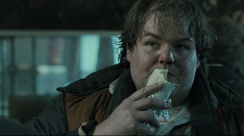 Movie still from “Submarino” (2010), directed by Thomas Vinterberg – A man eating a piece of food while sitting in a chair; Close Up shot, Over the shoulder angle