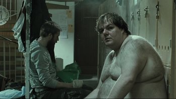 Movie still from “Submarino” (2010), directed by Thomas Vinterberg – A man sitting next to another man in a room; Medium shot, Low angle