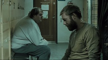 Movie still from “Submarino” (2010), directed by Thomas Vinterberg – Two men sitting on a chair in front of a door; Medium shot, Over the shoulder angle