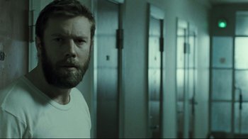Movie still from “Submarino” (2010), directed by Thomas Vinterberg – A man with a goatee standing in front of a wall; Close Up shot, Over the shoulder angle