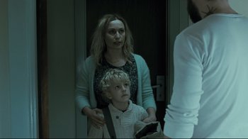 Movie still from “Submarino” (2010), directed by Thomas Vinterberg – A woman standing next to a child in a doorway; Medium shot, Over the shoulder angle
