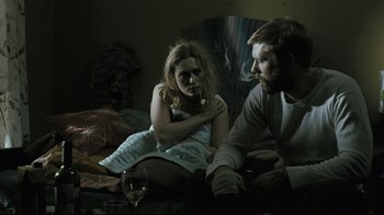 Movie still from “Submarino” (2010), directed by Thomas Vinterberg – A man and a woman sitting on a bed with a glass of wine; Medium shot, Over the shoulder angle