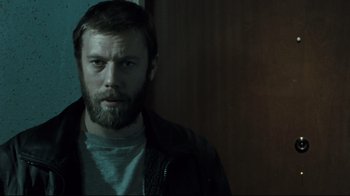Movie still from “Submarino” (2010), directed by Thomas Vinterberg – A man with a beard is standing in a room; Close Up shot, Low angle