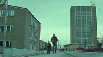 Movie still from “Submarino” (2010), directed by Thomas Vinterberg – A man and a boy are standing on the sidewalk; Extreme Wide shot, Low angle