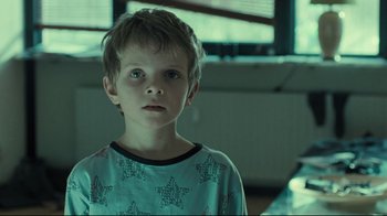 Movie still from “Submarino” (2010), directed by Thomas Vinterberg – A young boy in a blue shirt is looking at the camera; Close Up shot, Over the shoulder angle