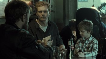 Movie still from “Submarino” (2010), directed by Thomas Vinterberg – A group of people sitting at a table with drinks; Medium shot, Over the shoulder angle