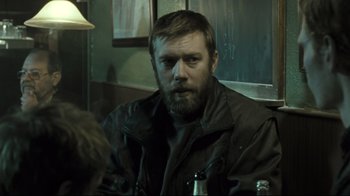 Movie still from “Submarino” (2010), directed by Thomas Vinterberg – A man sitting at a table with a beer in front of him; Medium shot, Over the shoulder angle