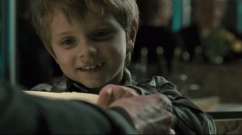 Movie still from “Submarino” (2010), directed by Thomas Vinterberg – A young boy smiling at the camera while holding his father's arm; Close Up shot, Over the shoulder angle