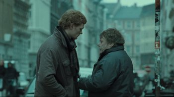 Movie still from “Submarino” (2010), directed by Thomas Vinterberg – Two men standing next to each other on a street; Medium shot, Over the shoulder angle
