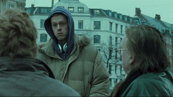 Movie still from “Submarino” (2010), directed by Thomas Vinterberg – A young man in a hooded jacket is standing next to an older man; Medium shot, Over the shoulder angle