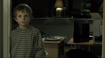 Movie still from “Submarino” (2010), directed by Thomas Vinterberg – A boy sitting in front of a television in a room; Medium shot, Over the shoulder angle
