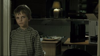 Movie still from “Submarino” (2010), directed by Thomas Vinterberg – A boy sitting in front of a tv in a room; Medium shot, Over the shoulder angle