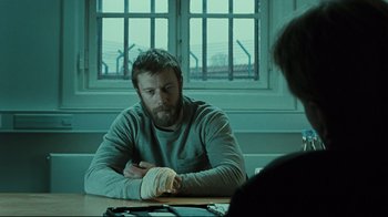 Movie still from “Submarino” (2010), directed by Thomas Vinterberg – A man sitting at a table in front of a window; Medium shot, Over the shoulder angle