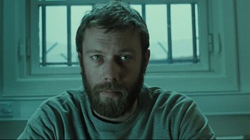 Movie still from “Submarino” (2010), directed by Thomas Vinterberg – A man with a goatee and a beard stares at the camera; Close Up shot, Low angle