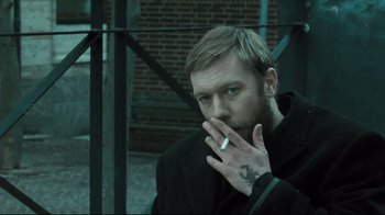 Movie still from “Submarino” (2010), directed by Thomas Vinterberg – A man smoking a cigarette while sitting on a bench; Close Up shot, High angle