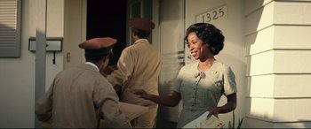 Movie still from “Suburbicon” (2017), directed by George Clooney – An african american woman in a brown dress; Medium shot, Low angle