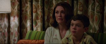 Movie still from “Suburbicon” (2017), directed by George Clooney – A person sitting on a couch with a child; Medium shot, Over the shoulder angle