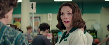 Movie still from “Suburbicon” (2017), directed by George Clooney – A woman in a white and green shirt in front of a store; Medium shot, Over the shoulder angle