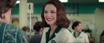 Movie still from “Suburbicon” (2017), directed by George Clooney – A woman in a green and white uniform smiling; Close Up shot, Over the shoulder angle