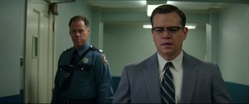 Movie still from “Suburbicon” (2017), directed by George Clooney – A man in a suit and tie standing next to another man in a suit and tie; Close Up shot, Low angle