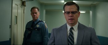 Movie still from “Suburbicon” (2017), directed by George Clooney – A man in a suit and tie standing next to another man in a suit and tie; Close Up shot, Low angle