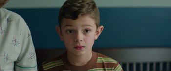 Movie still from “Suburbicon” (2017), directed by George Clooney – A young boy with brown hair and a striped shirt; Close Up shot, High angle