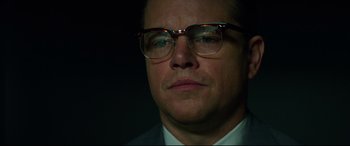 Movie still from “Suburbicon” (2017), directed by George Clooney – A person wearing a suit and glasses; Close Up shot, Low angle