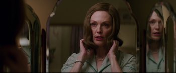 Movie still from “Suburbicon” (2017), directed by George Clooney – A woman in a white shirt is putting on a necklace; Close Up shot, Low angle